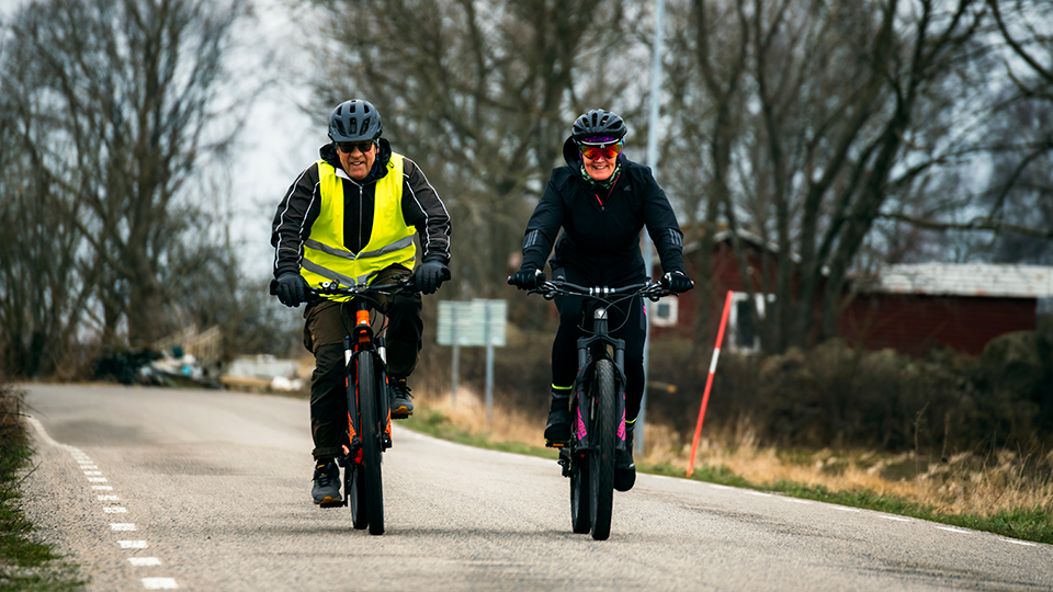 En man och en kvinna cyklar på en liten landsväg