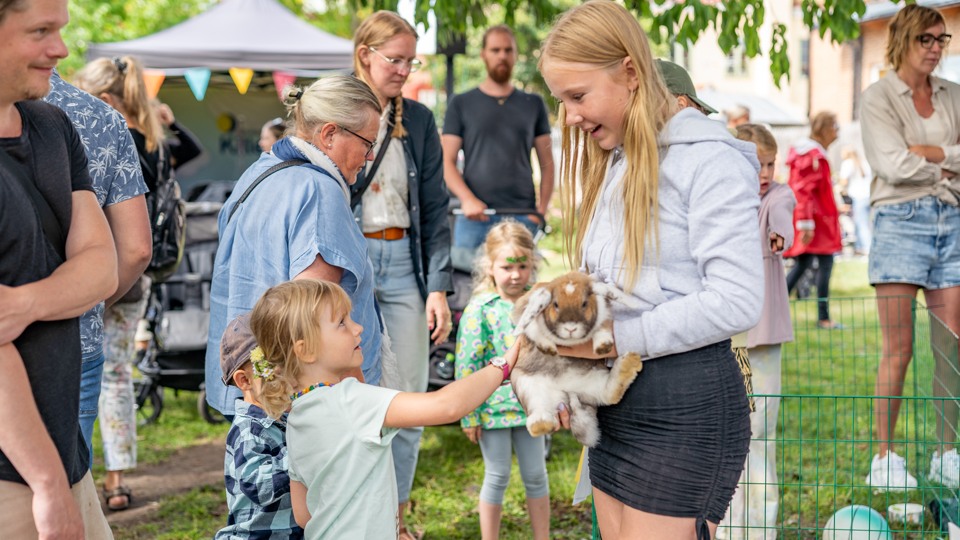 En flicka håller upp sin kanin så barnen kan klappa den.