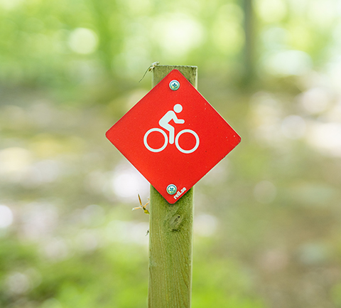 En orange skylt med en bild på en vit cykel. Skylten visar att det är en markerad cykelled.