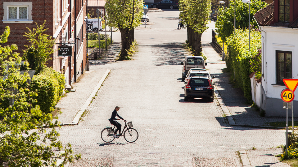 En cyklist på Sölvesborgs kullerstensgator en solig vårdag