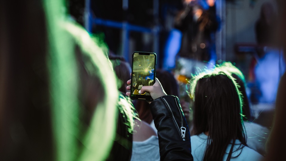 En tjej håller upp en mobil och fotar ett uppträde på Killebom