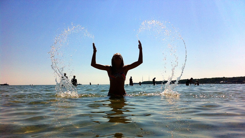 En flicka badar och skvätter vatten som formar ett hjärta ovanför hennes huvud.