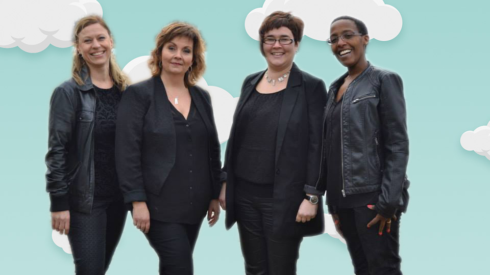 Fyra kvinnliga sångerskor på rad klädda i svart.