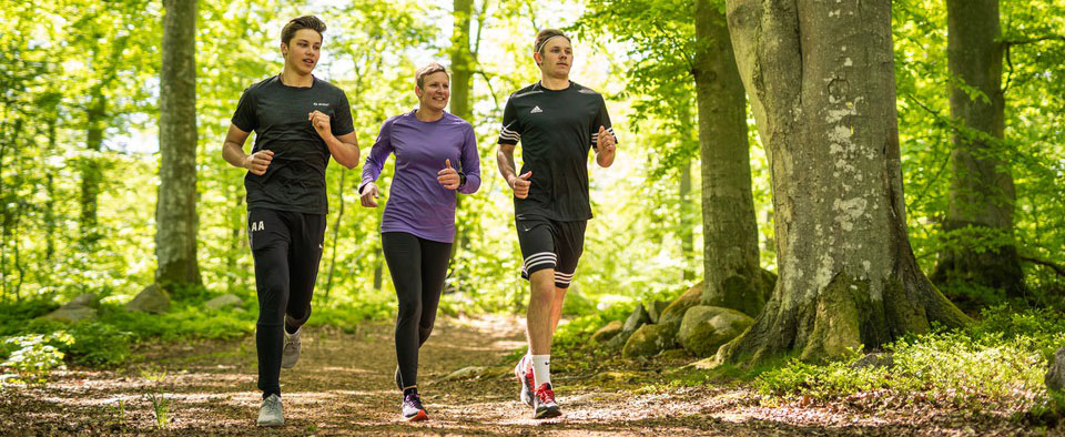 Tre personer joggar bredvid varandra på på löparslingan som går i skogen vid Svarta Ledsområdet. Fotograf: André Julinder   