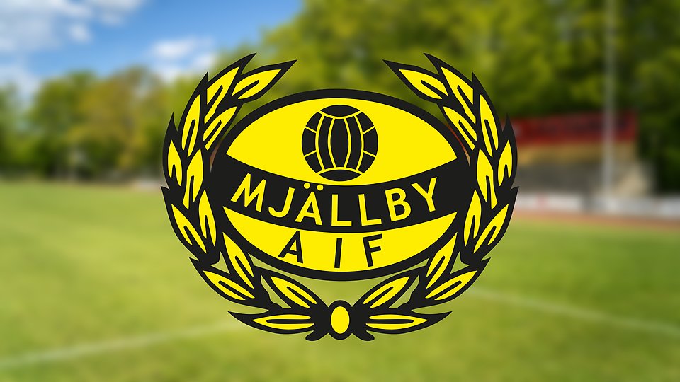 Det allsvenskalaget MAIFs logotyp på en oskarp bakgrund som föreställer en fotbollsplan på idrottsplatsen Svarta led.