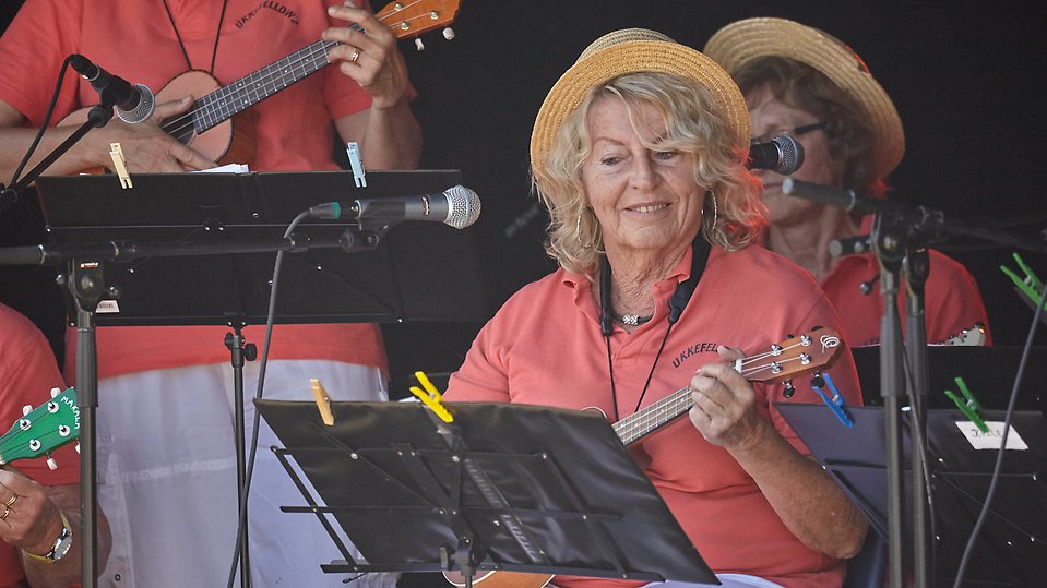 En kvinna i hatt spelar ukulele